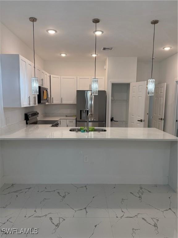 kitchen with a peninsula, white cabinetry, light countertops, appliances with stainless steel finishes, and pendant lighting