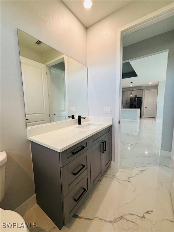 bathroom featuring toilet, recessed lighting, vanity, baseboards, and marble finish floor