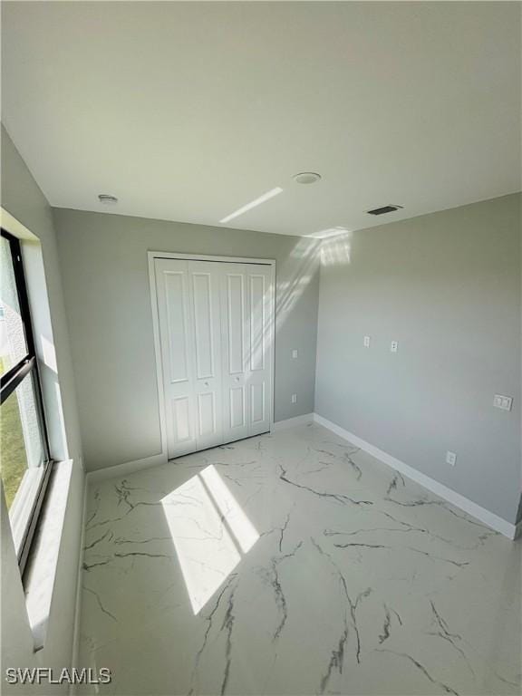 unfurnished bedroom featuring marble finish floor and baseboards