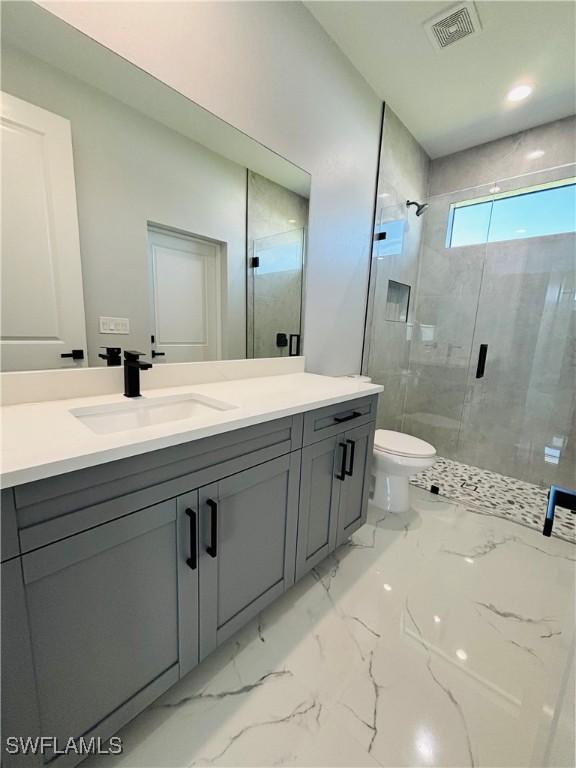 full bathroom with marble finish floor, visible vents, toilet, a stall shower, and vanity