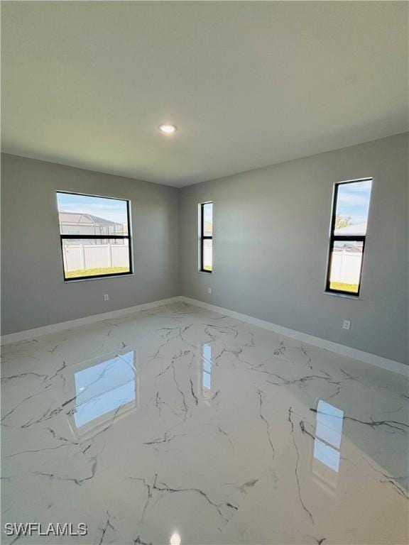 empty room with recessed lighting, marble finish floor, and baseboards