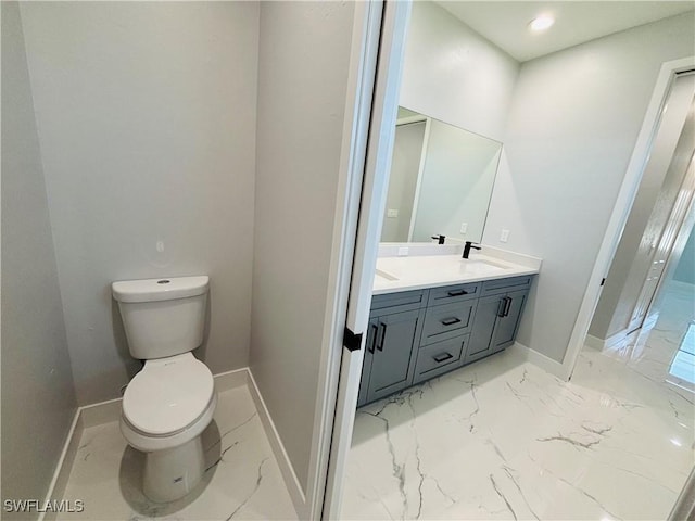 bathroom featuring marble finish floor, baseboards, a sink, and toilet