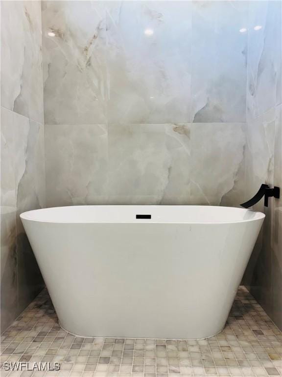 full bathroom with a freestanding tub and tile walls