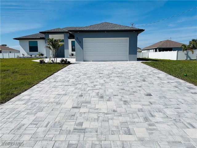 prairie-style house with a front lawn, decorative driveway, fence, and stucco siding