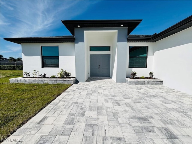 entrance to property with a lawn and stucco siding