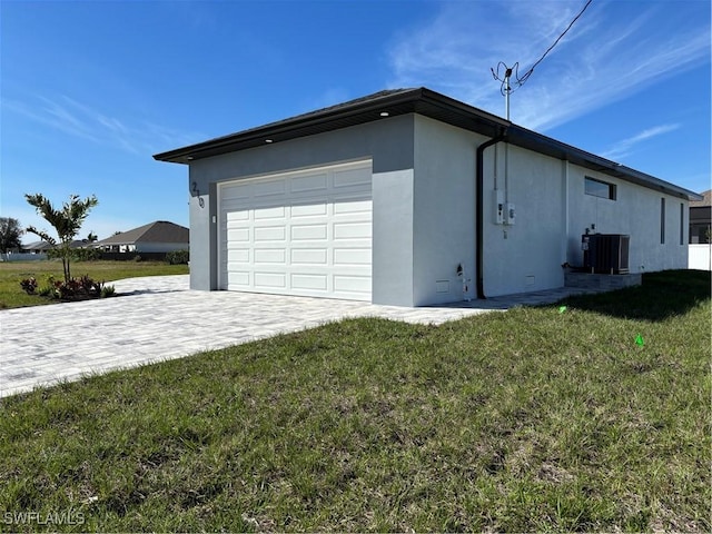 garage with decorative driveway and central air condition unit