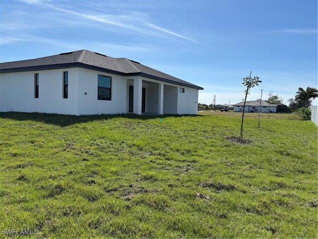 back of property featuring a lawn and stucco siding