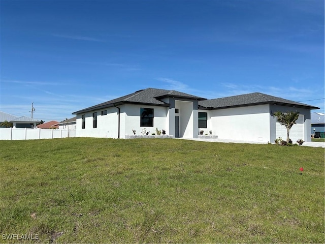 prairie-style home featuring a front yard, fence, and stucco siding