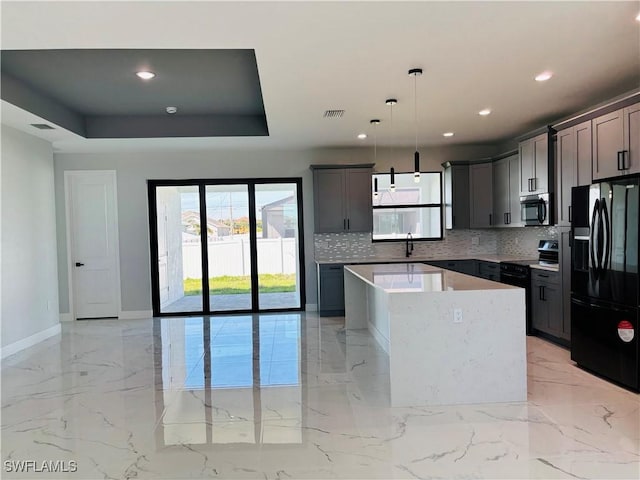 kitchen with a center island, marble finish floor, a tray ceiling, a sink, and black appliances