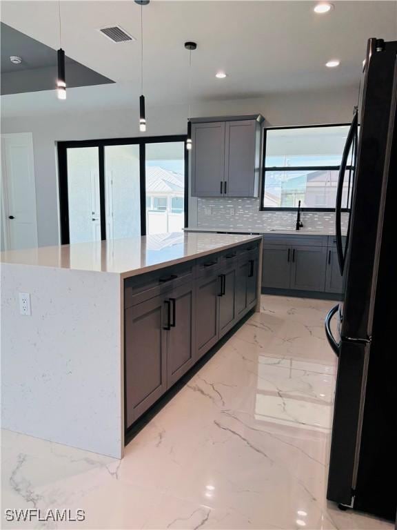 kitchen featuring visible vents, marble finish floor, plenty of natural light, and freestanding refrigerator