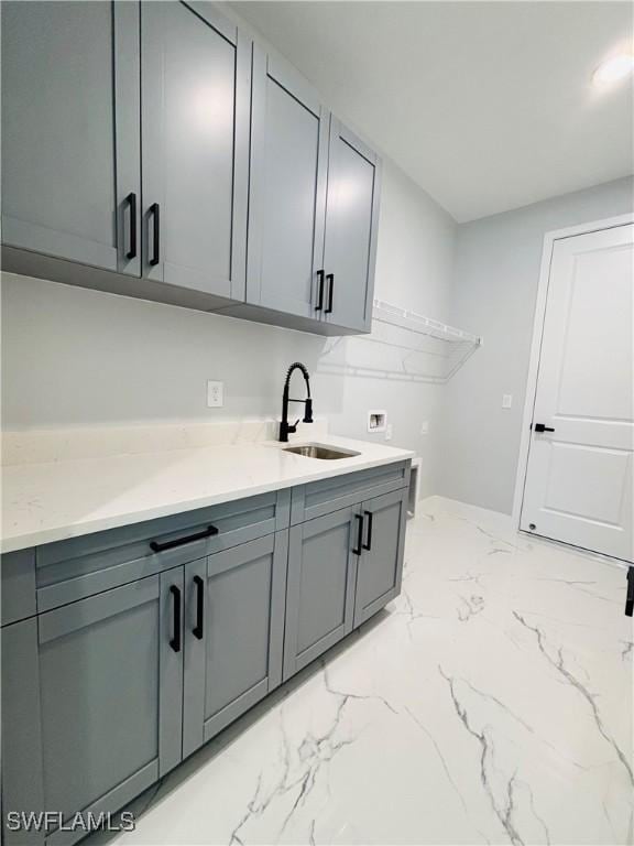 interior space with light stone counters, gray cabinets, a sink, and marble finish floor