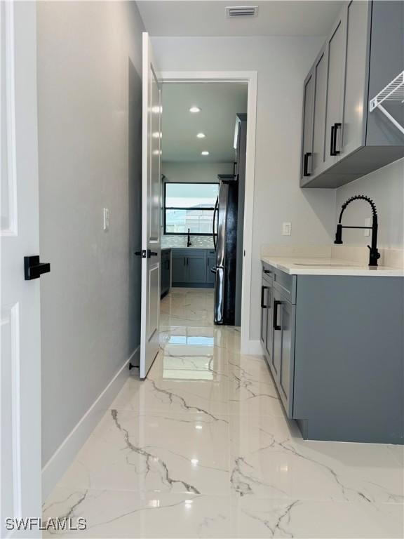 interior space featuring marble finish floor, a sink, visible vents, and baseboards