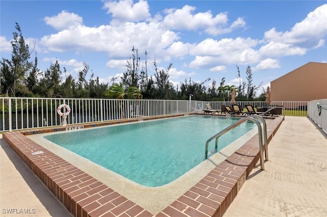 pool with a water view, fence, and a patio