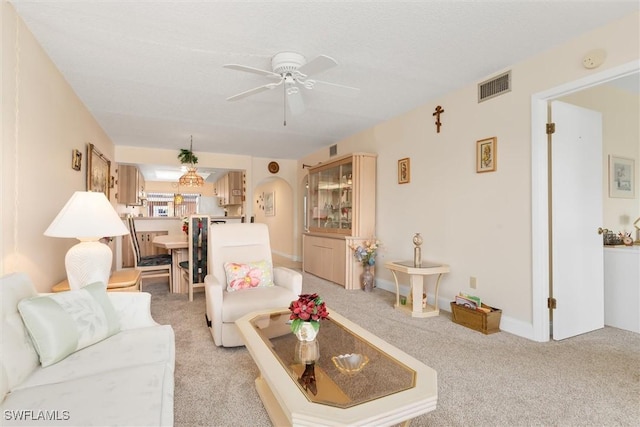 living area with a ceiling fan, light colored carpet, visible vents, and arched walkways