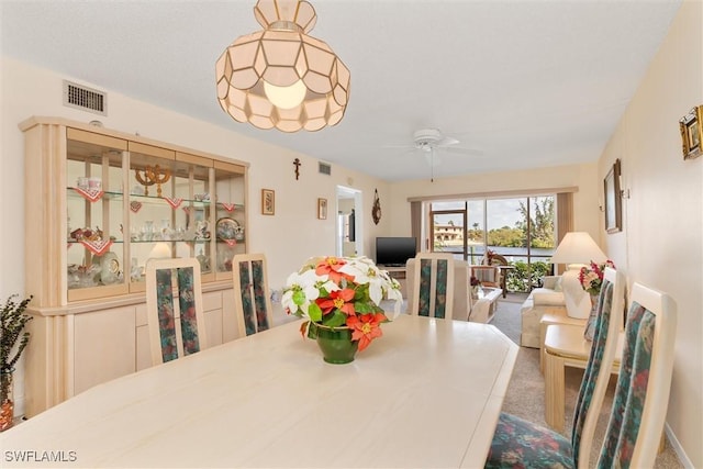 carpeted dining room with ceiling fan and visible vents