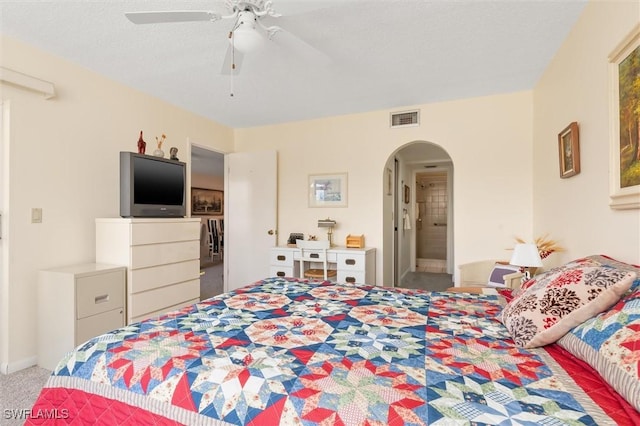 bedroom with light colored carpet, arched walkways, visible vents, and ceiling fan