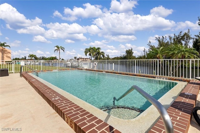 pool featuring a patio area, a water view, and fence