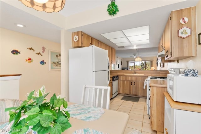 kitchen featuring a peninsula, white appliances, light countertops, and a sink