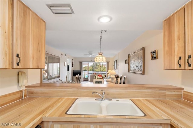 kitchen with visible vents, wood counters, open floor plan, pendant lighting, and a sink