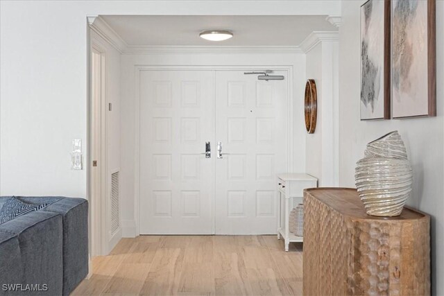 foyer entrance with light wood-style floors, visible vents, and crown molding