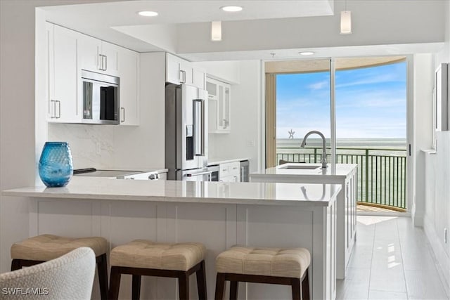980 Cape Marco Dr Unit 805, Marco Island, FL 34145 - kitchen with high end refrigerator, a sink, tasteful backsplash, a breakfast bar area, and white cabinetry