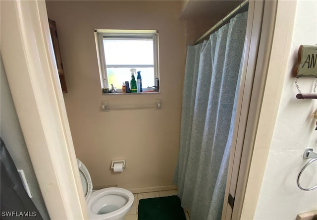 bathroom with toilet, a shower with curtain, and baseboards