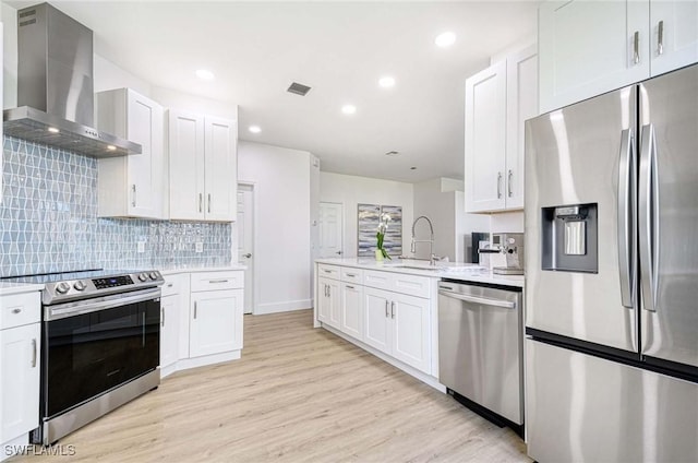 kitchen featuring light wood-style floors, wall chimney exhaust hood, visible vents, and stainless steel appliances