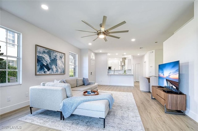 living area featuring light wood-style floors, baseboards, and recessed lighting