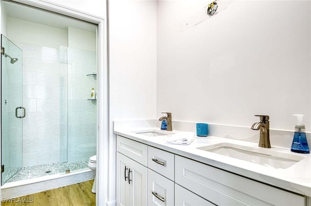 bathroom with wood finished floors, a stall shower, a sink, and toilet