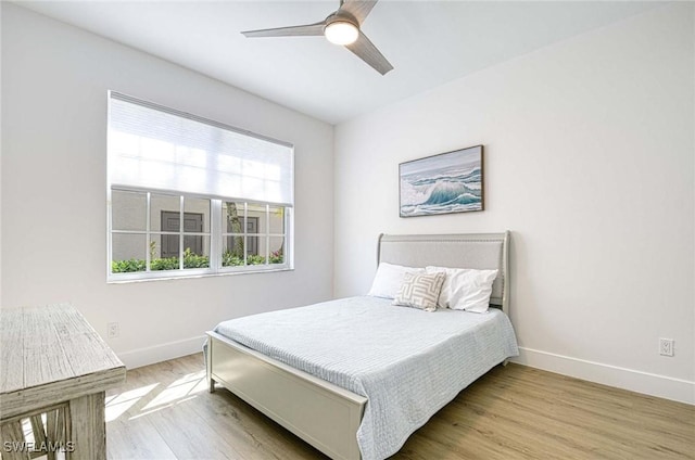 bedroom featuring a ceiling fan, baseboards, and wood finished floors