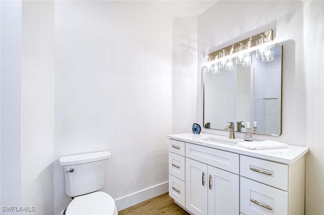 bathroom with vanity, wood finished floors, toilet, and baseboards