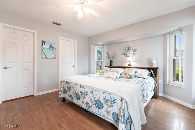 bedroom featuring visible vents, ceiling fan, baseboards, and wood finished floors