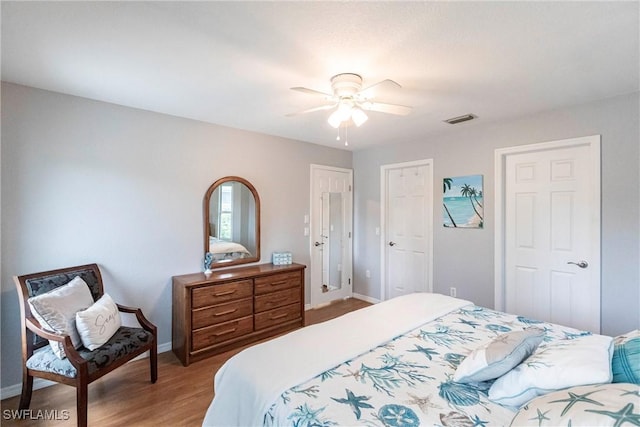 bedroom with light wood finished floors, baseboards, visible vents, ceiling fan, and a closet