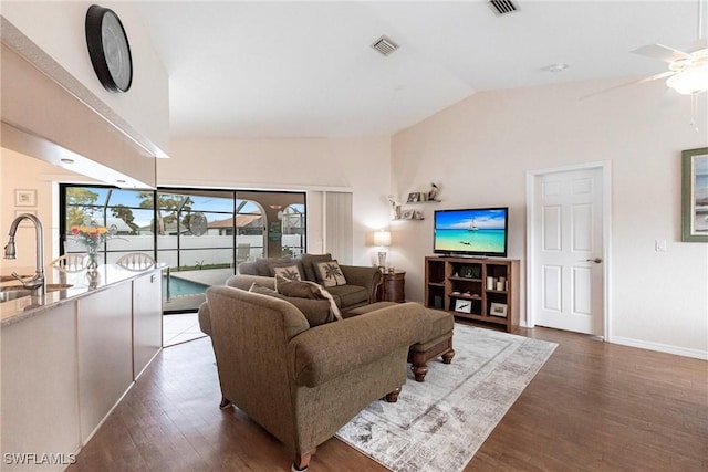 living area featuring baseboards, visible vents, ceiling fan, dark wood-type flooring, and vaulted ceiling