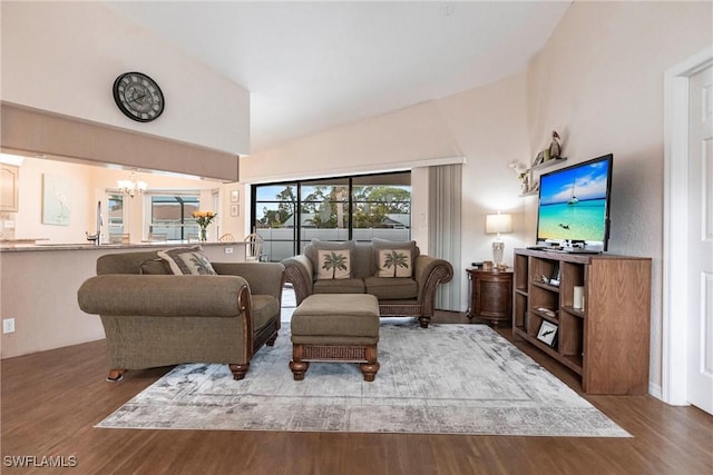 living room with a chandelier, high vaulted ceiling, and wood finished floors