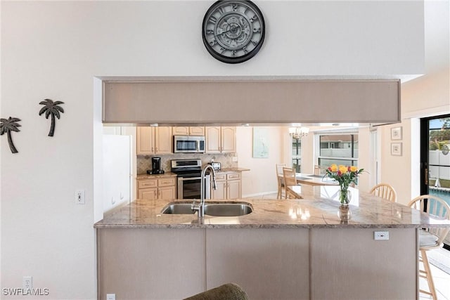 kitchen featuring a breakfast bar area, stainless steel appliances, backsplash, a sink, and a peninsula