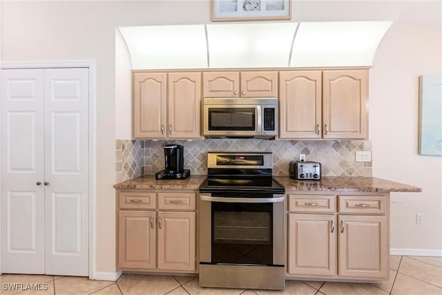 kitchen with appliances with stainless steel finishes, tasteful backsplash, and light brown cabinetry