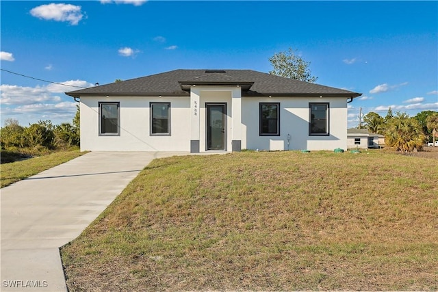 rear view of house featuring a lawn and stucco siding