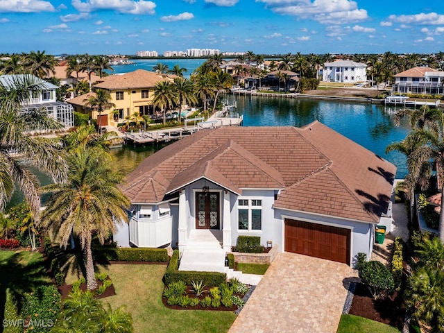 view of front facade with a garage, decorative driveway, a water view, and a residential view