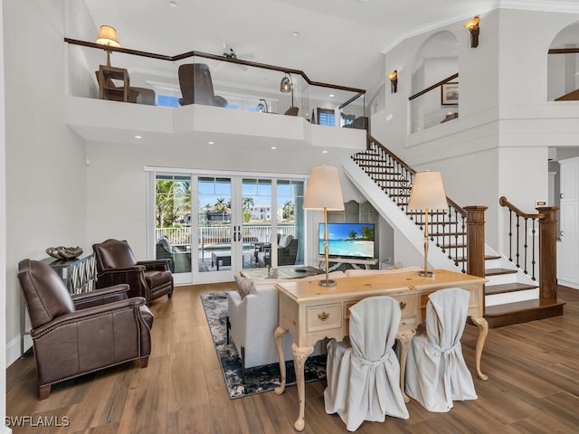 living room featuring stairs, french doors, wood finished floors, and a towering ceiling