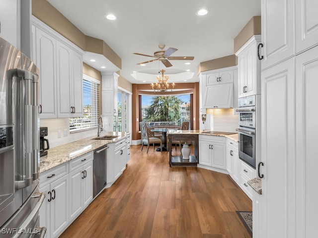 kitchen with a sink, white cabinets, appliances with stainless steel finishes, decorative backsplash, and dark wood finished floors