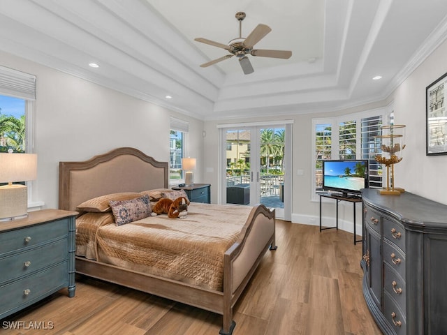 bedroom featuring a tray ceiling, french doors, light wood-style floors, ornamental molding, and access to outside