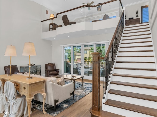 living room with french doors, a towering ceiling, light wood finished floors, and stairs