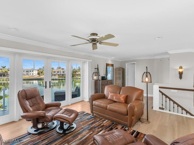 living area with a ceiling fan, wood finished floors, a water view, crown molding, and french doors