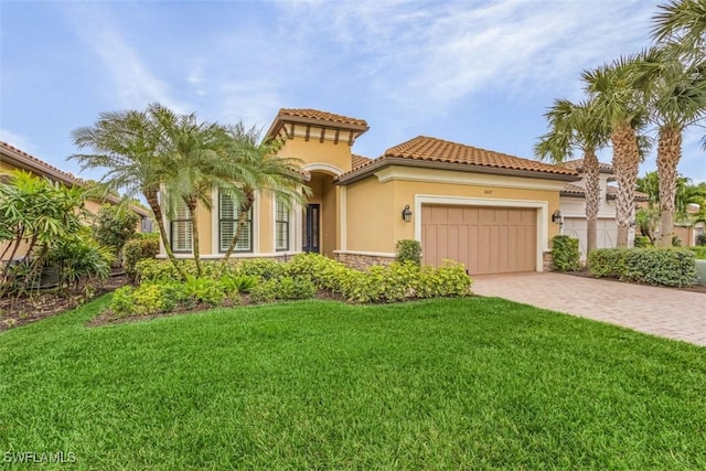 mediterranean / spanish-style home featuring a garage, stone siding, decorative driveway, stucco siding, and a front lawn