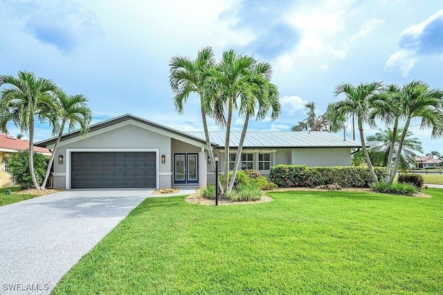 view of front facade featuring driveway, metal roof, an attached garage, a front lawn, and stucco siding