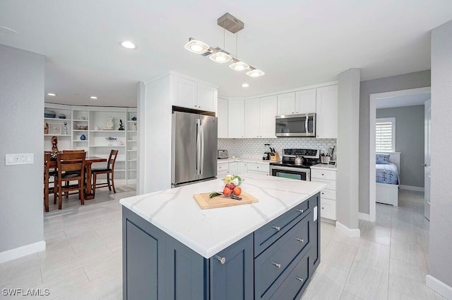 kitchen featuring appliances with stainless steel finishes, a center island, white cabinetry, and light stone countertops