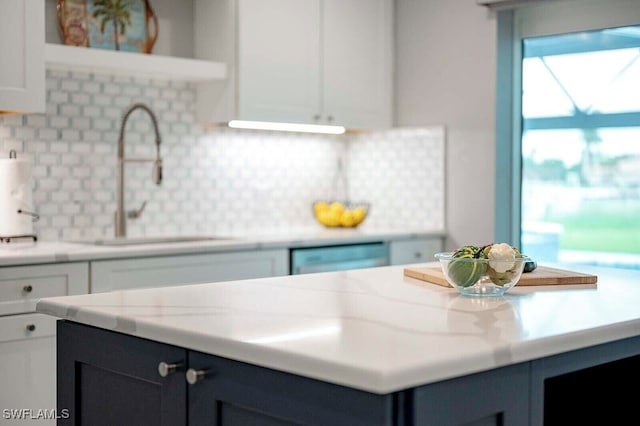 kitchen featuring light stone counters, white cabinetry, a sink, and dishwashing machine