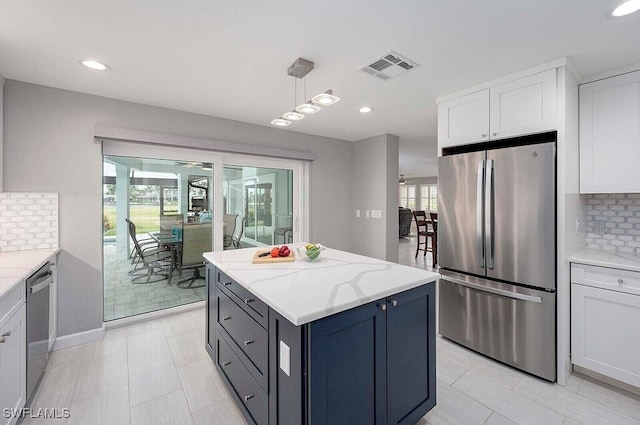 kitchen with appliances with stainless steel finishes, white cabinetry, hanging light fixtures, and light stone counters