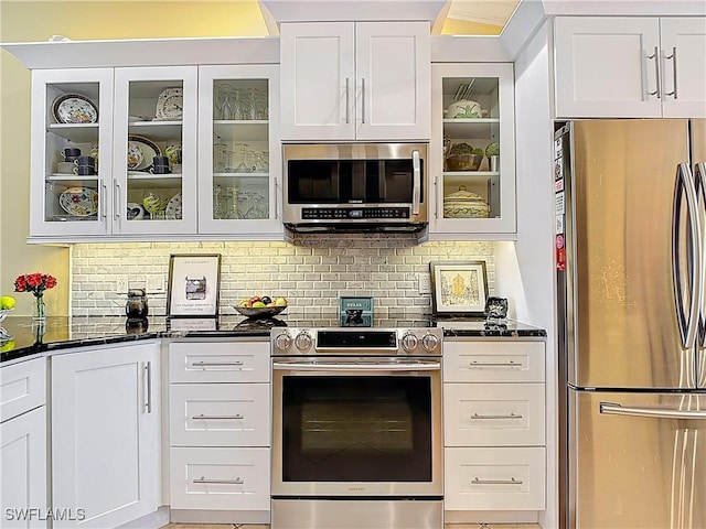 kitchen featuring white cabinets, glass insert cabinets, stainless steel appliances, and decorative backsplash